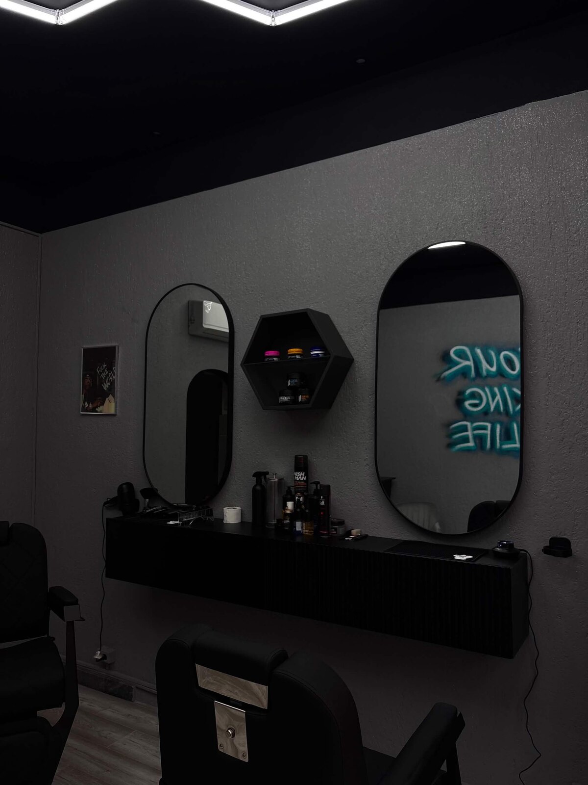 Interijer BASE Barbershopa, crni namještaj, ovalna ogledala i neonski natpis